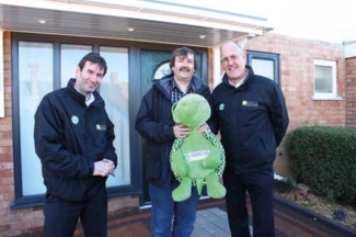 Brett Smith (left) and David Bertorelli (right) from Abacus Healthcare present Leigh with a cuddy Trevor the Turtle for his son