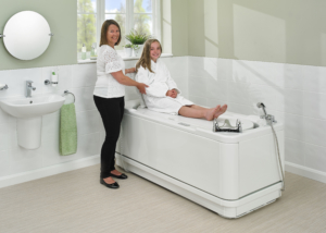 Carer and girl using the lowering platform on a Gemini1700 bath