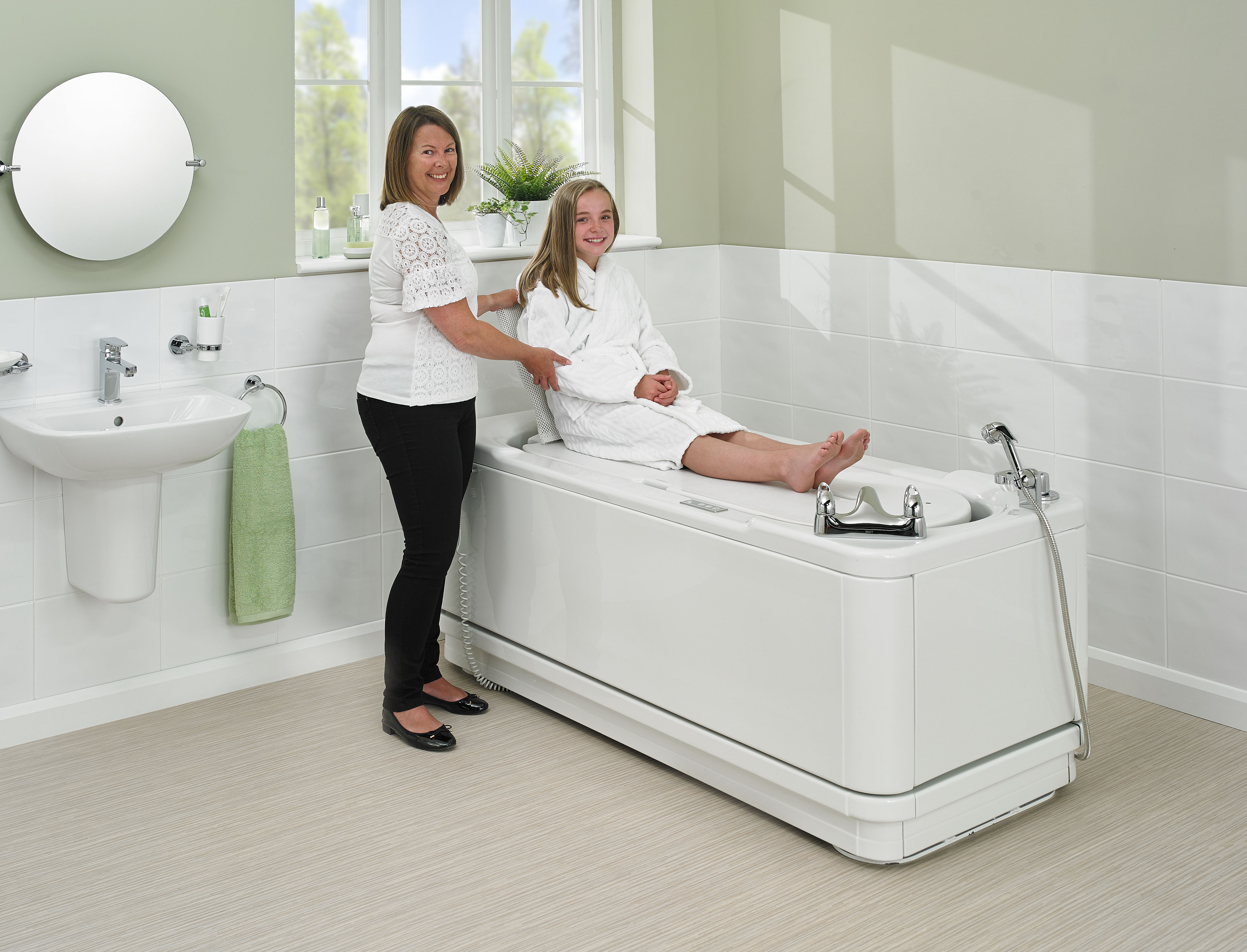 Carer and girl using the lowering platform on a Gemini1700 bath